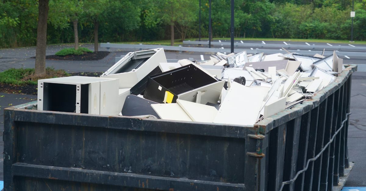 A dumpster filled with junk is sitting in a parking lot.