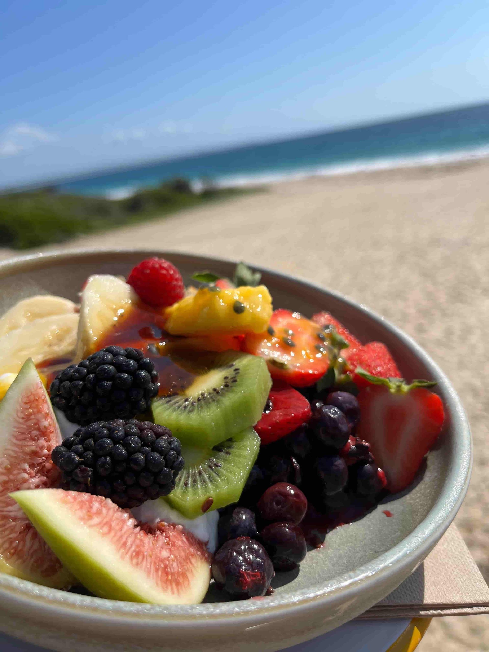 A Bowl Of Fruit Is Sitting On A Table On The Beach — Beach Bums Cafe In Forster, NSW