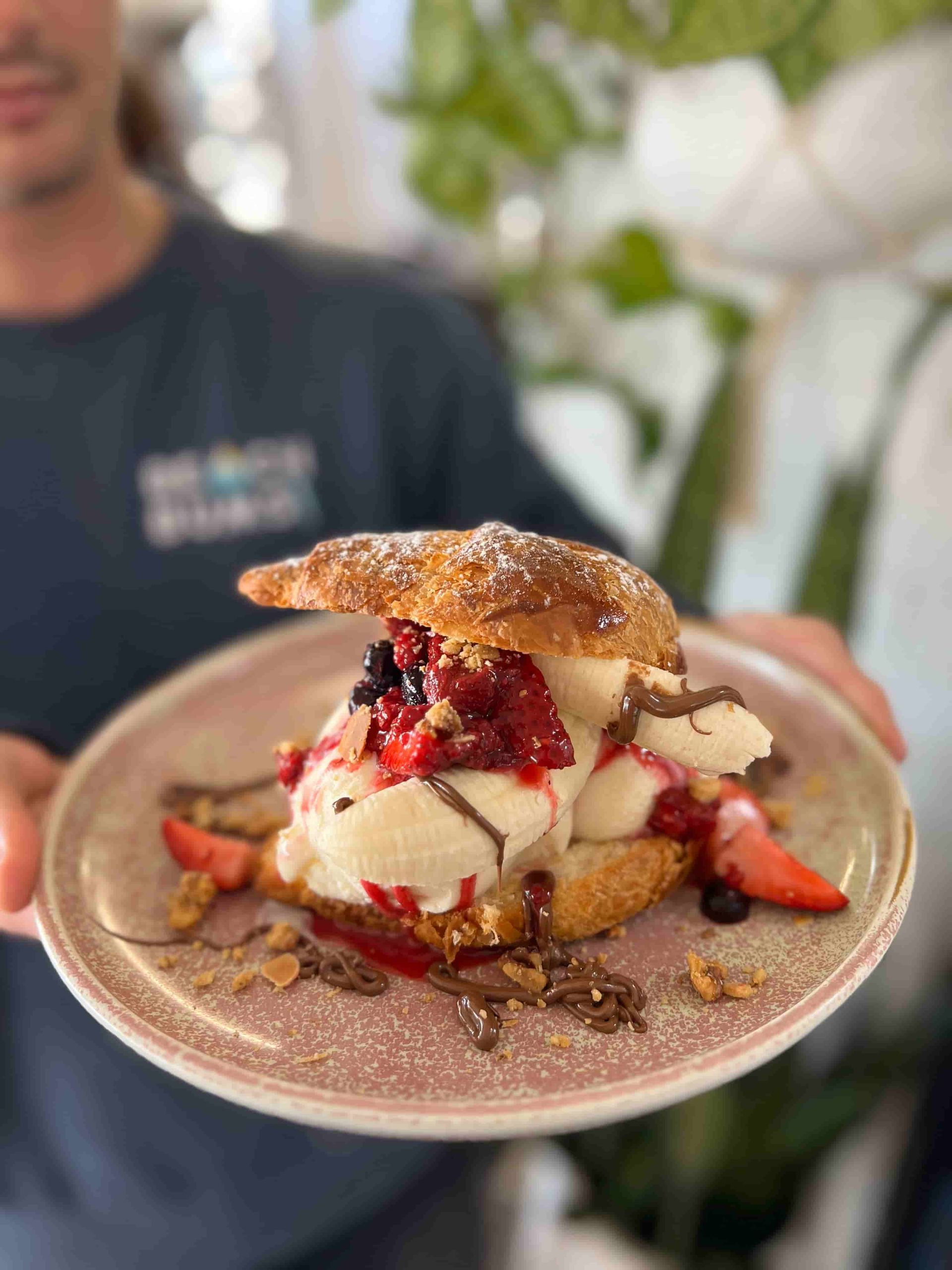 A Man Is Holding A Plate Of Food With Ice Cream And Berries On It — Beach Bums Cafe In Forster, NSW