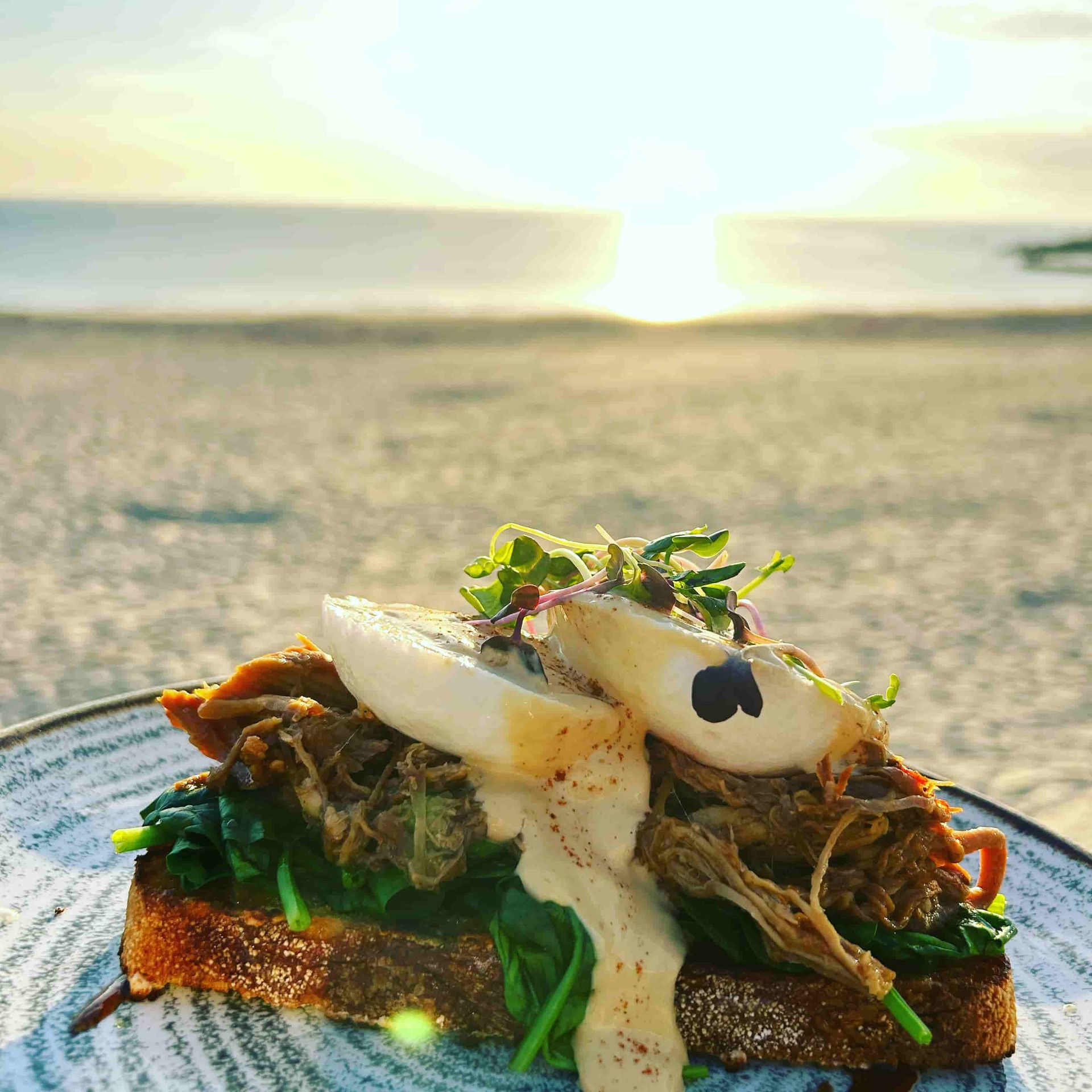 A Plate Of Food On A Table With A Beach In The Background — Beach Bums Cafe In Forster, NSW