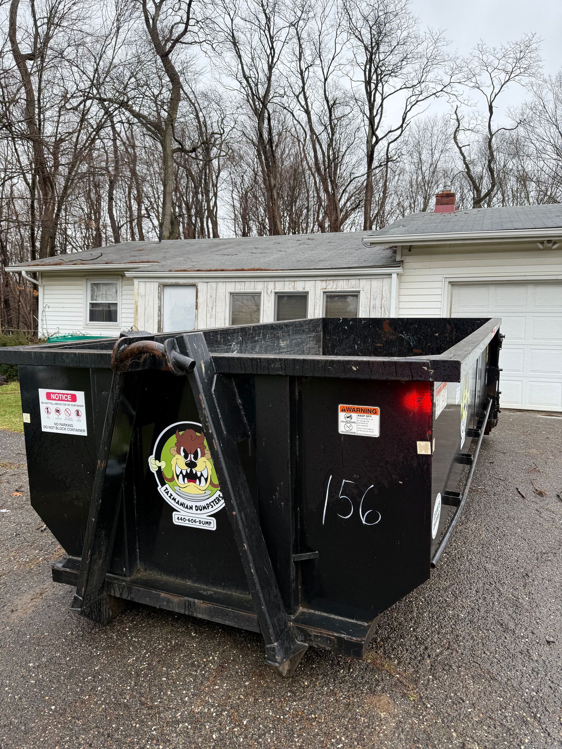 A dumpster is parked in front of a house.