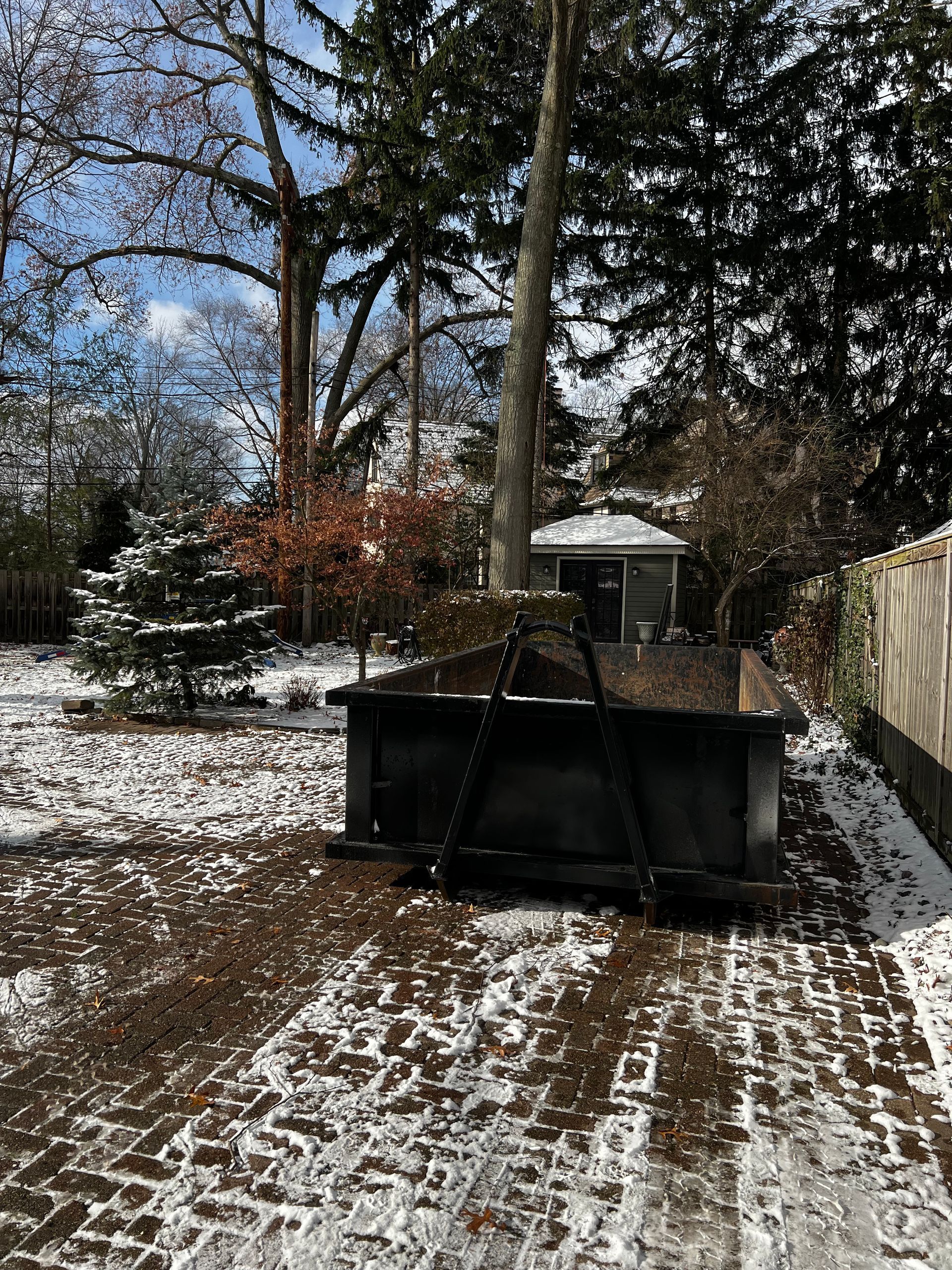 A snow plow is sitting in the middle of a snowy yard.