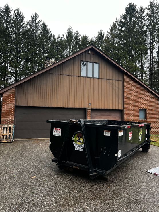 A dumpster is parked in front of a brick building.