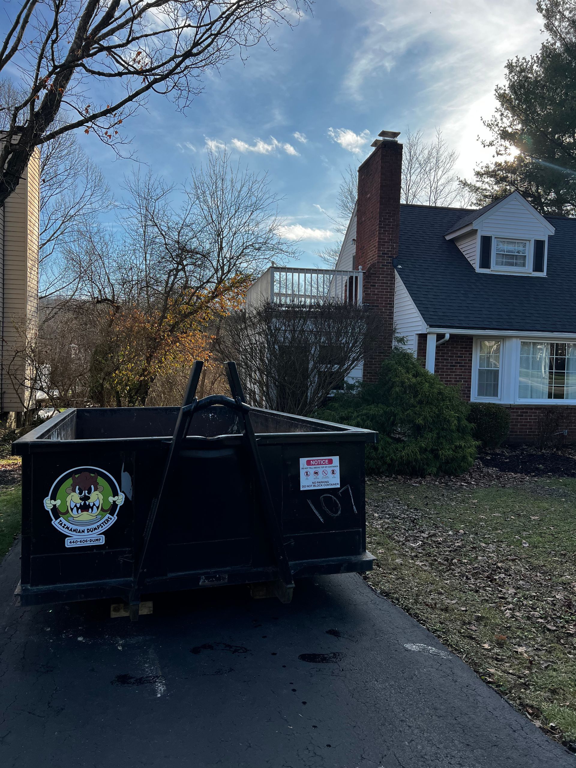 A dumpster is parked in front of a house.