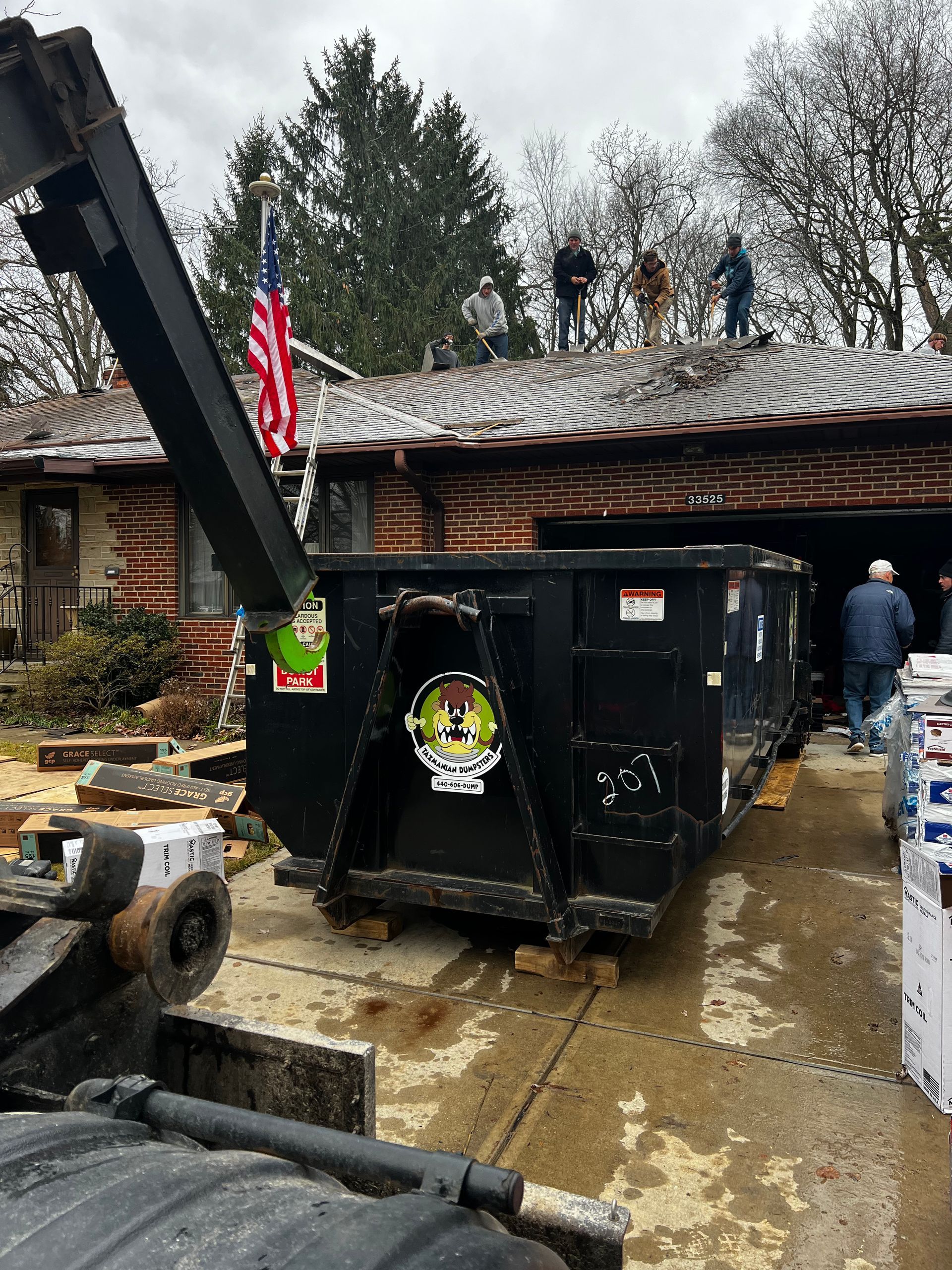 A dumpster is sitting in front of a brick house.