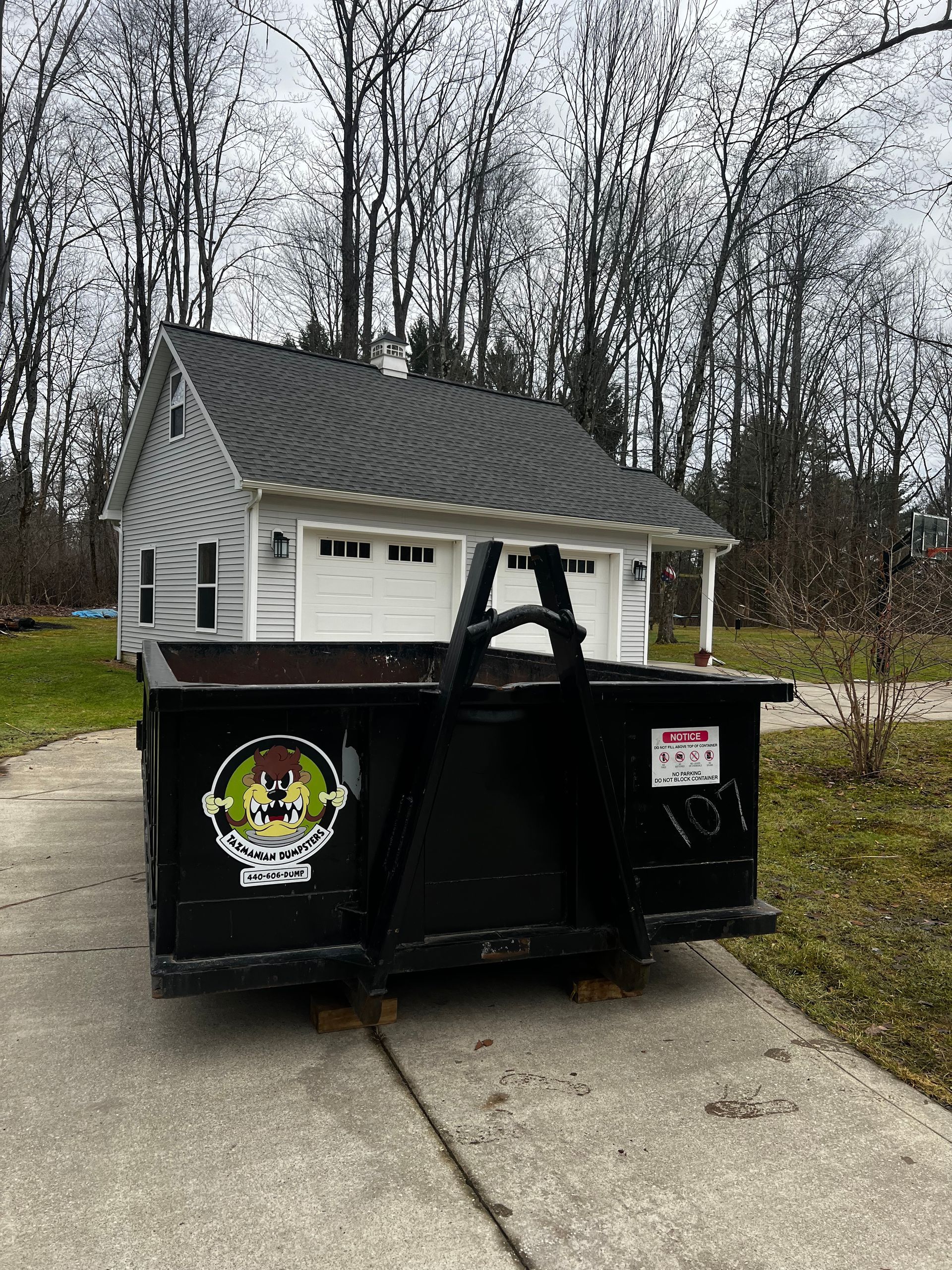 A dumpster is parked in front of a house.