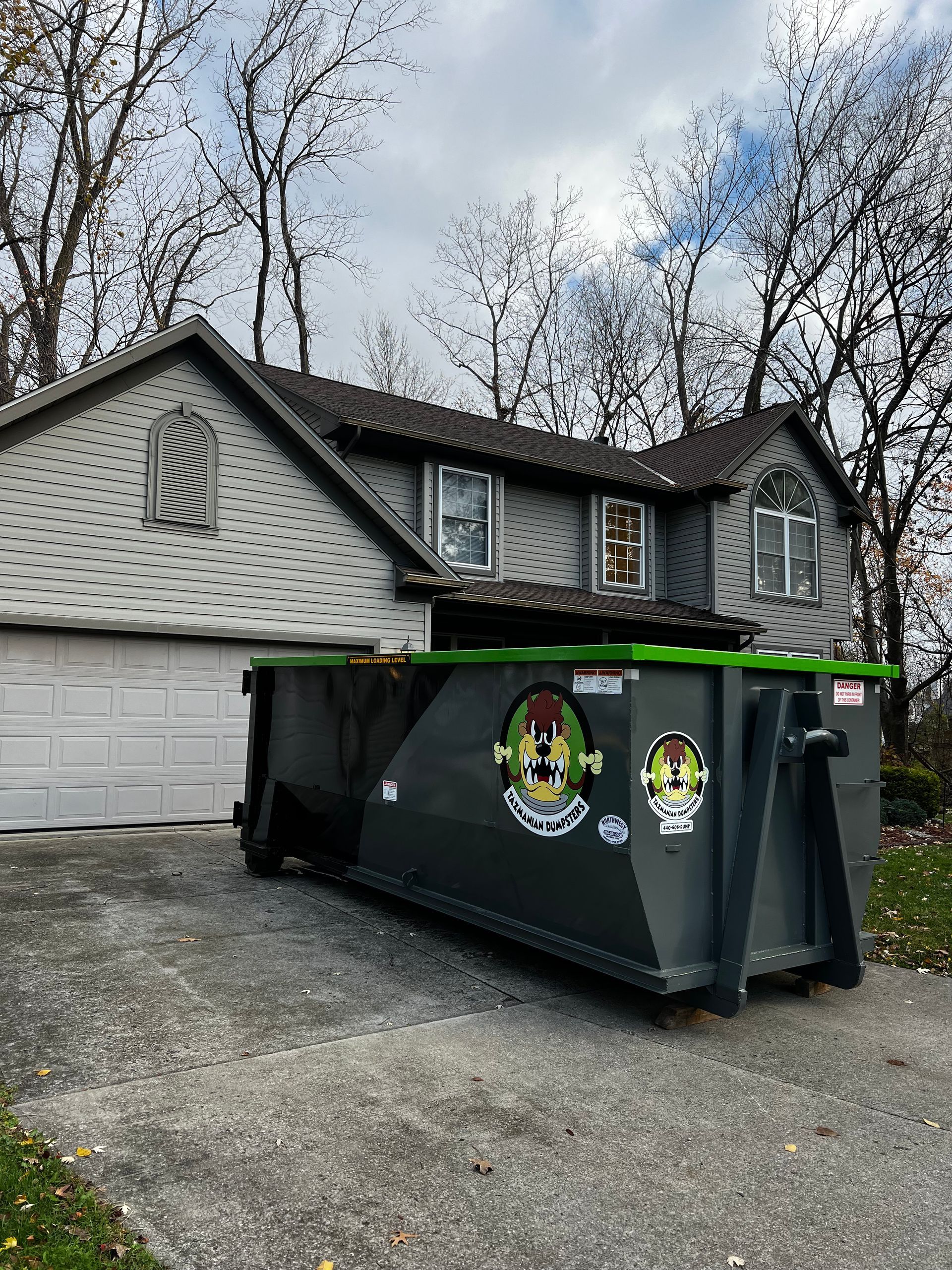 A dumpster is parked in front of a house.