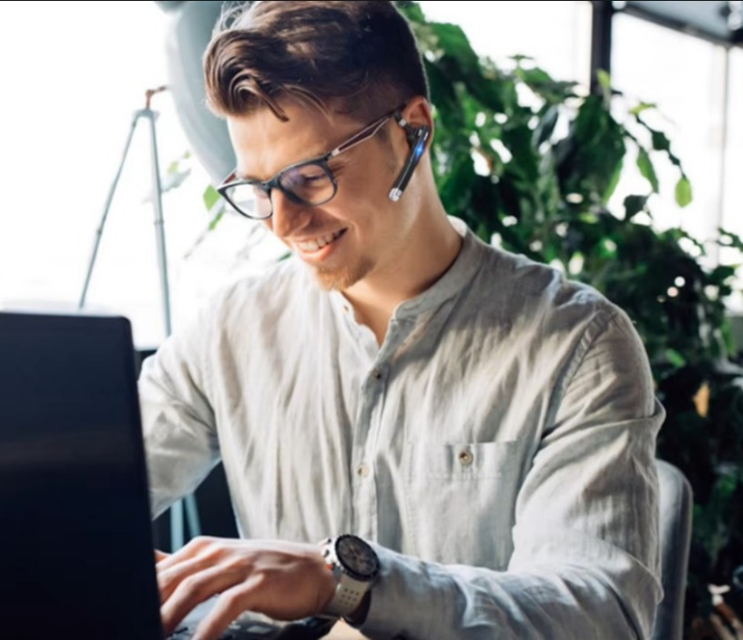 Mujer con auriculares y hombre mirando una tableta en una cocina, el hombre está gesticulando, ambos están sonriendo.