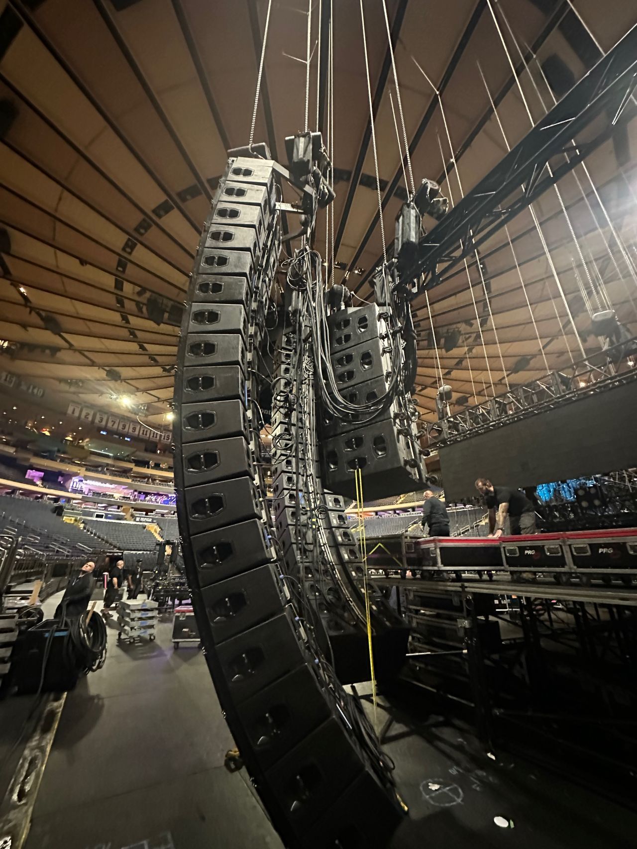 A row of speakers hanging from the ceiling of a stadium