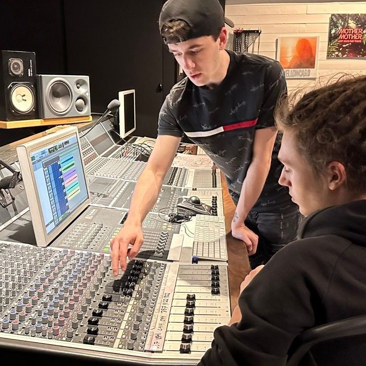 A man is teaching another man how to use a mixer