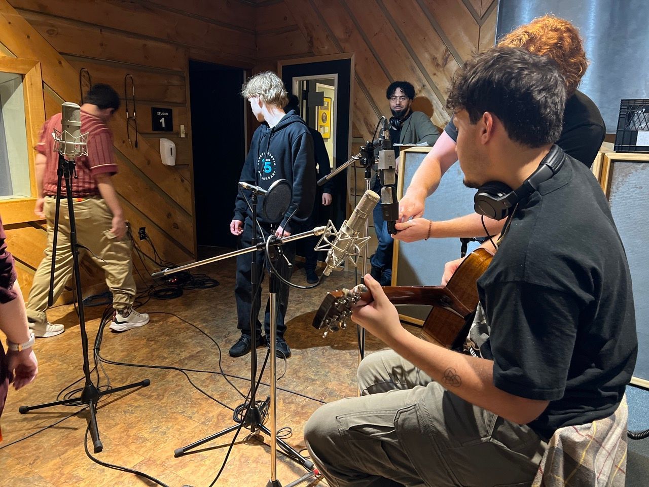 A group of people are playing instruments in a recording studio.