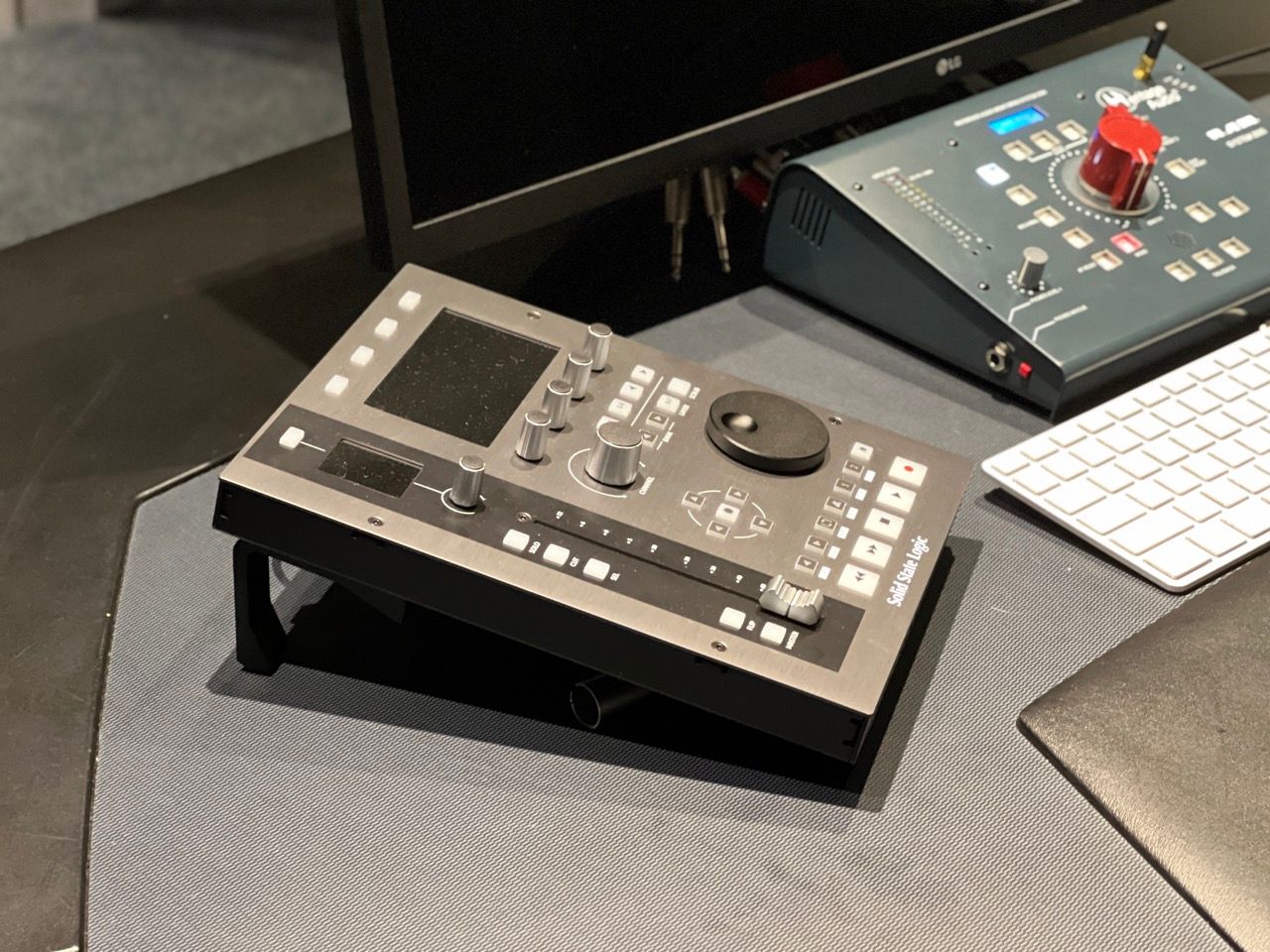 A black device is sitting on a desk next to a keyboard and monitor.
