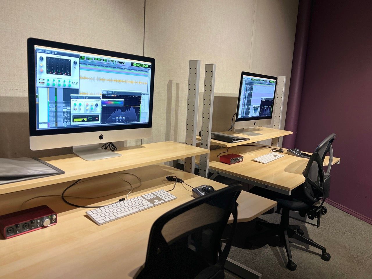 Two computer monitors are sitting on top of wooden desks in a room.