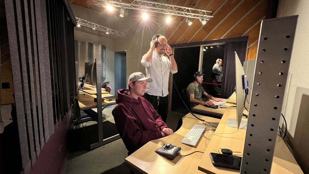 A group of people are sitting at desks in front of computer monitors.