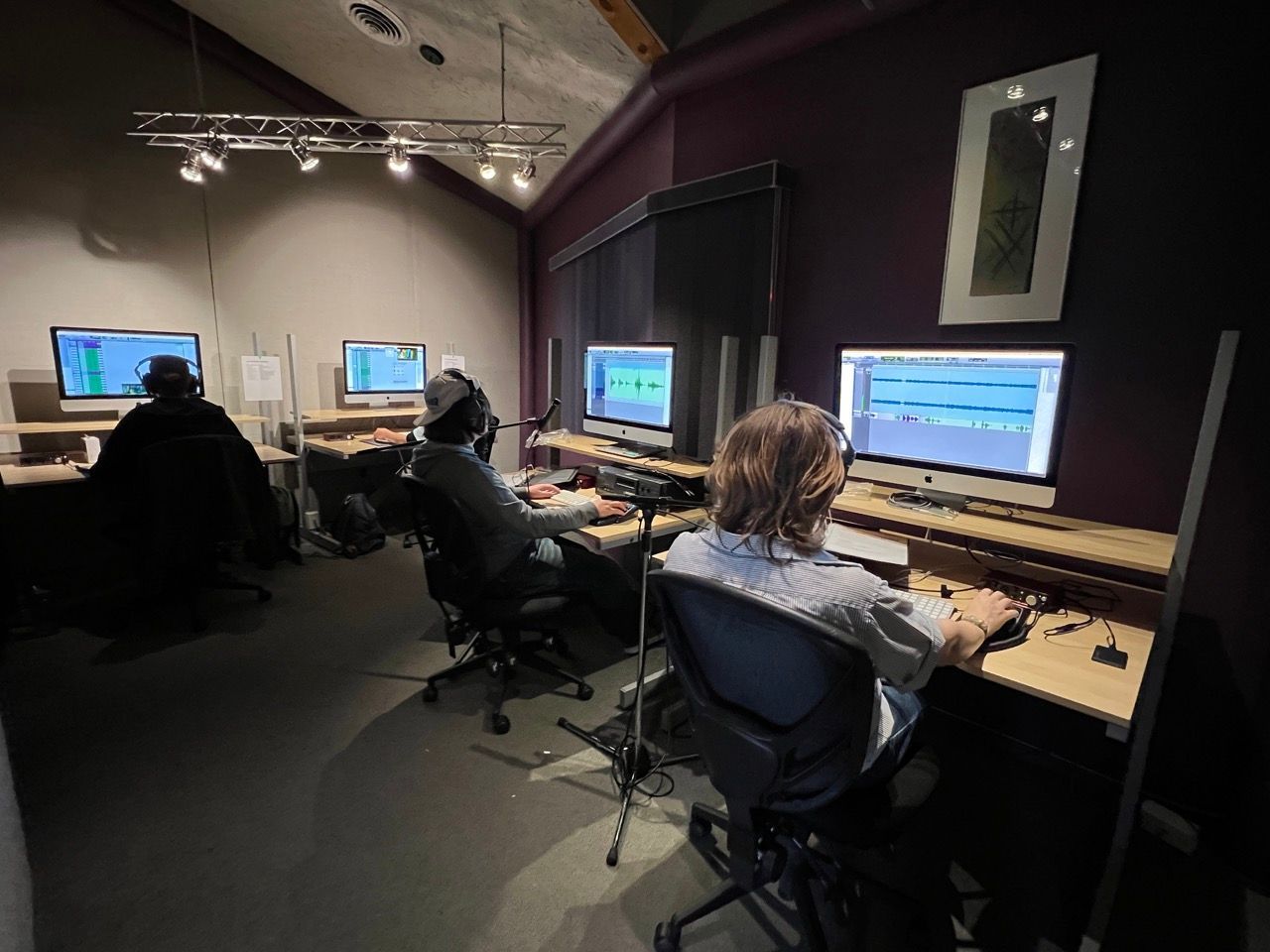 A man is sitting in front of a computer in a recording studio.