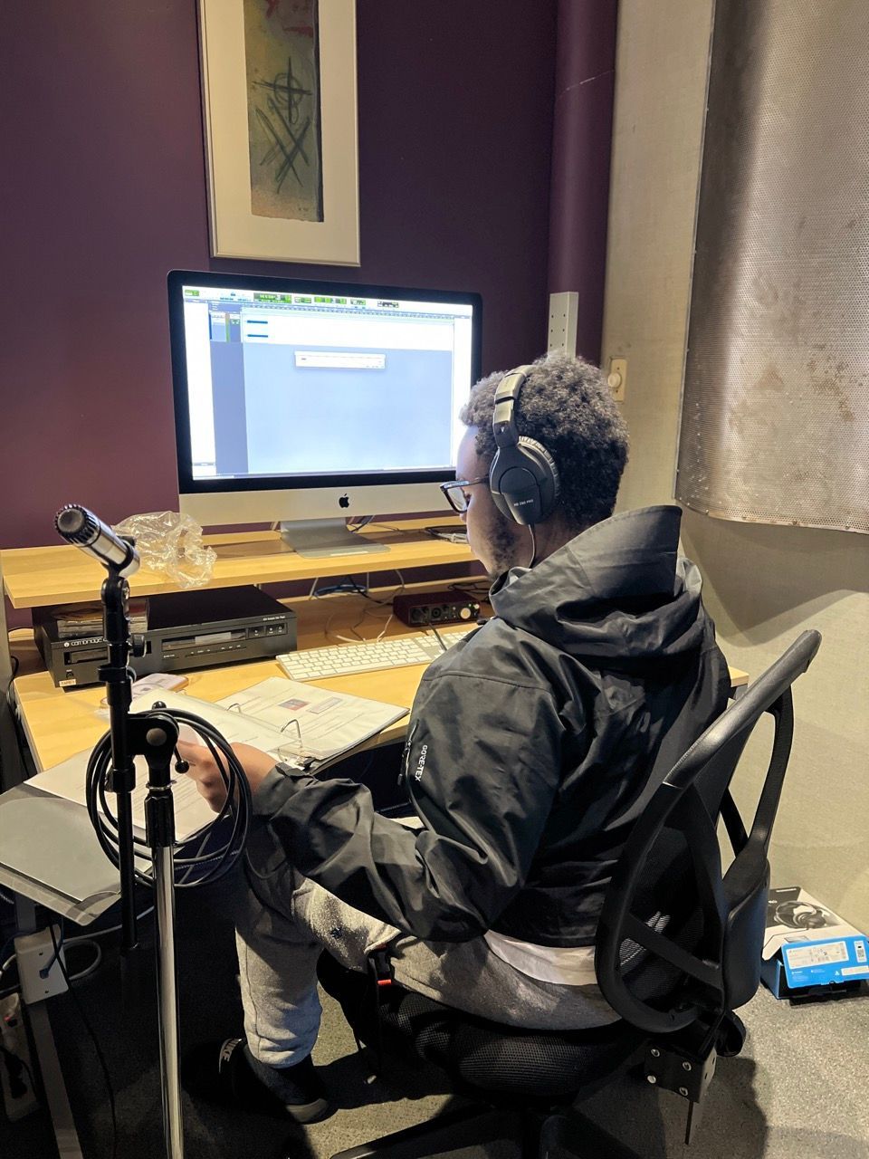 A man wearing headphones is sitting in front of a computer.