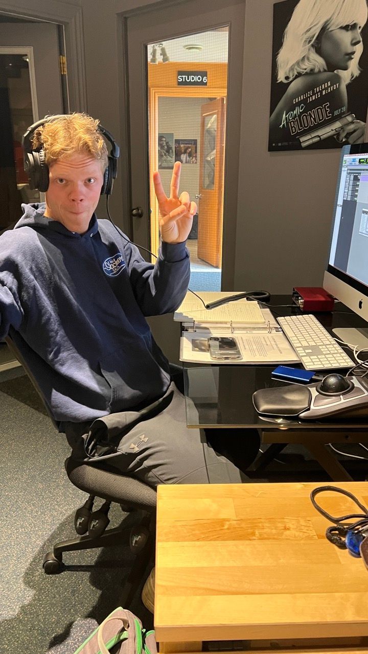 A man wearing headphones is sitting at a desk in front of a computer.