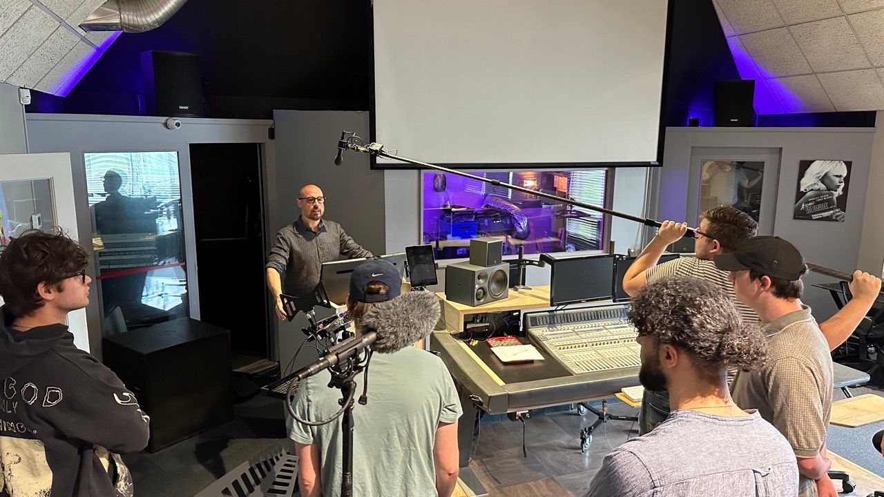A group of people are standing in a room in front of a projector screen.
