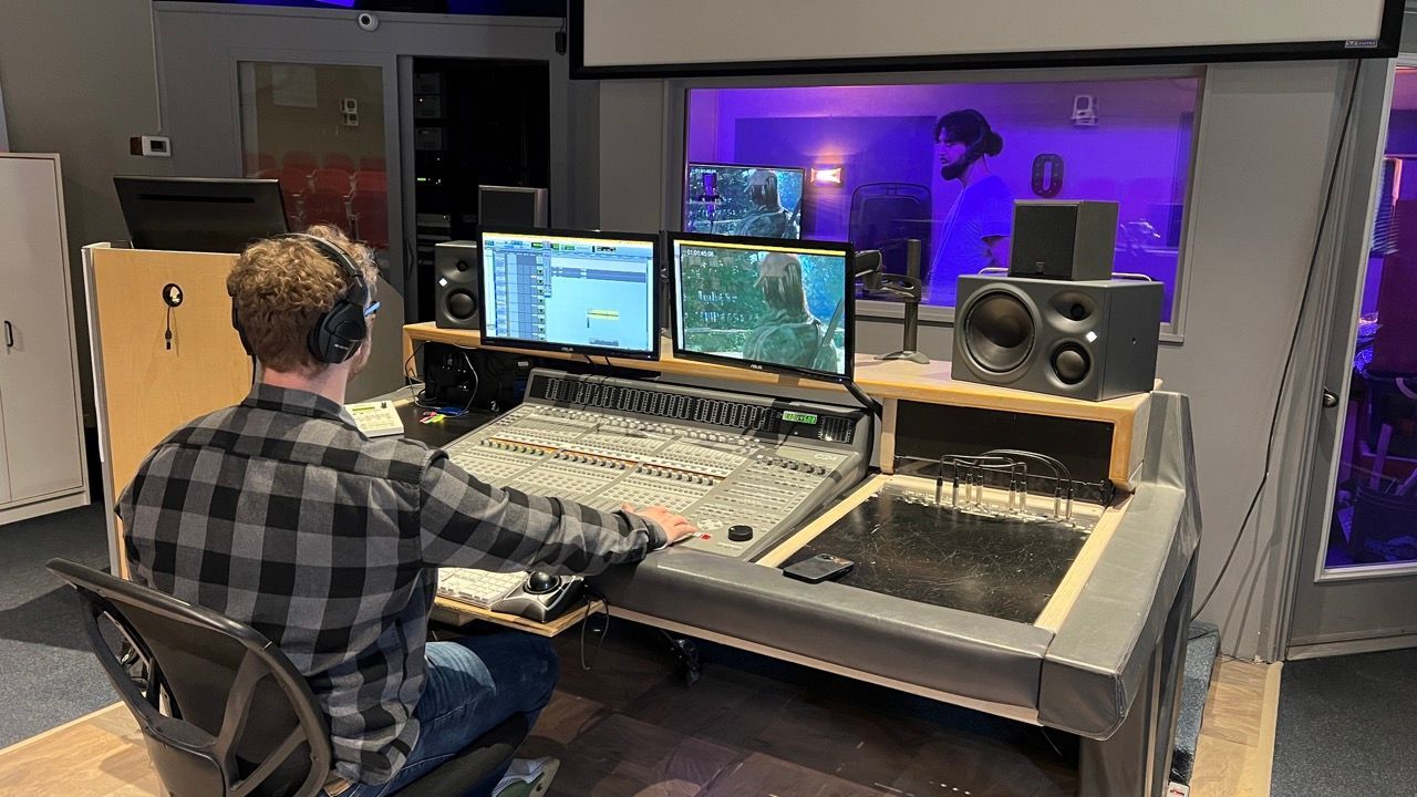 A man is sitting at a desk in a recording studio.