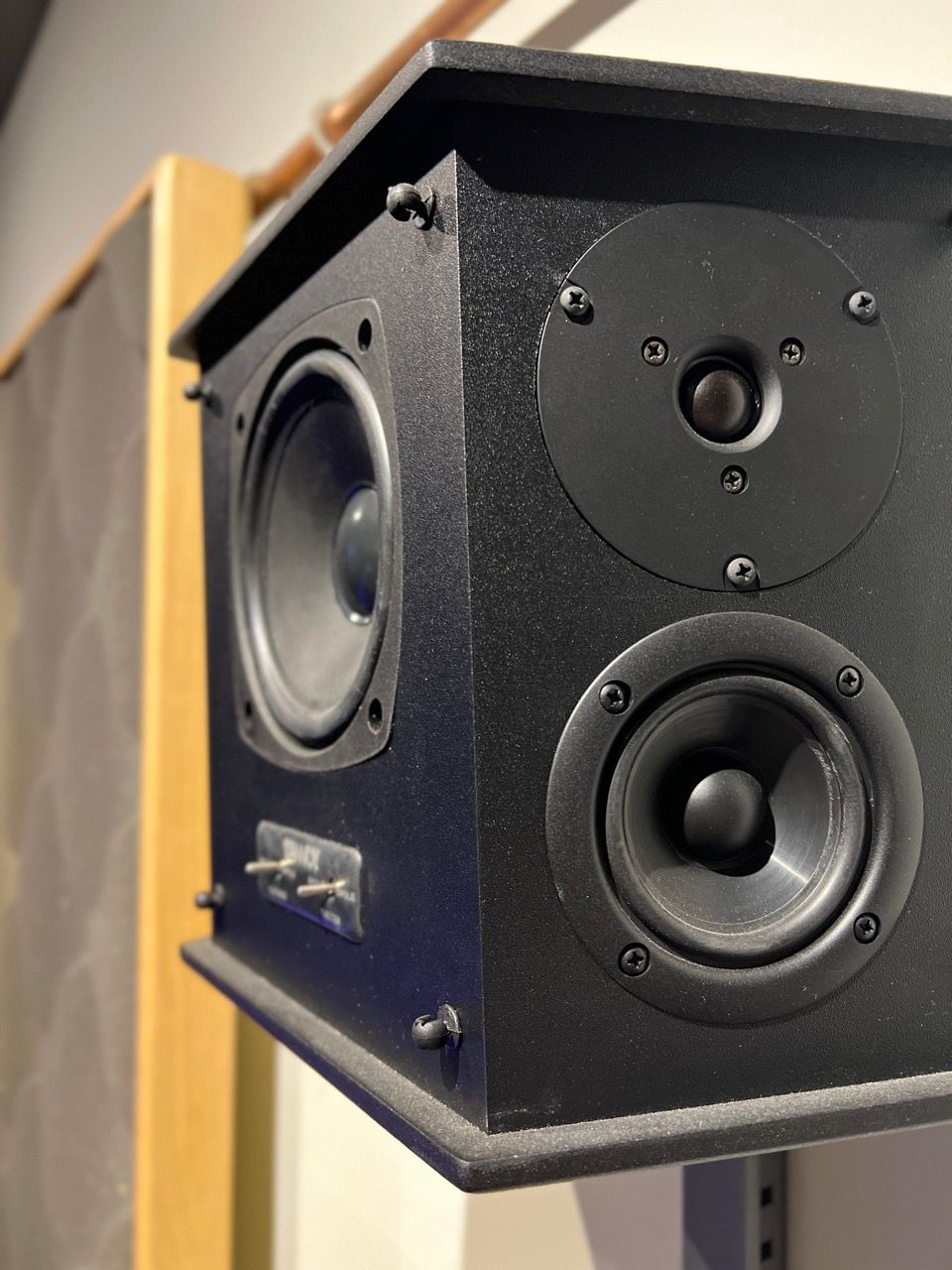 A close up of a black speaker hanging on a wall