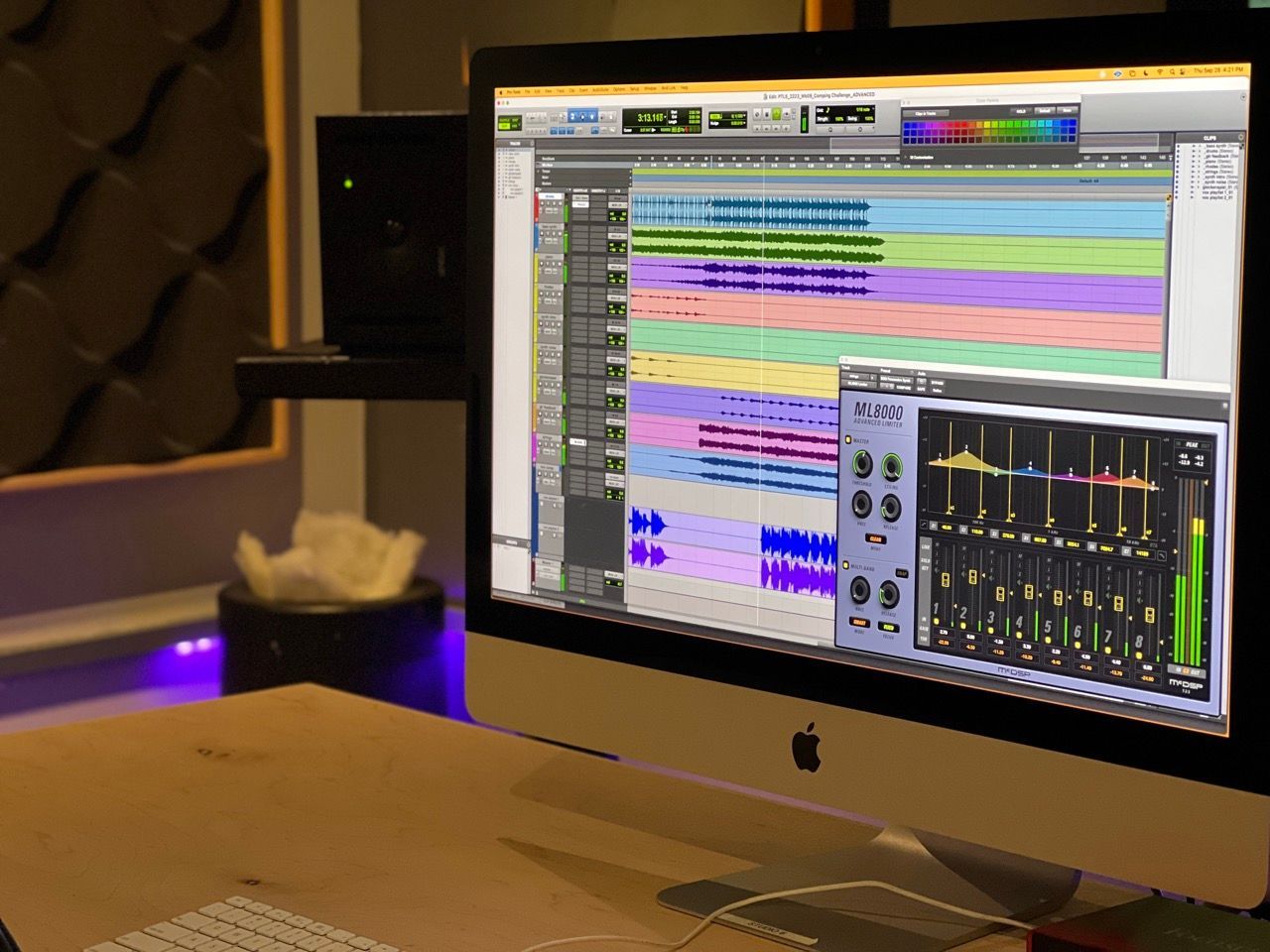 An apple computer is sitting on a desk in a recording studio.