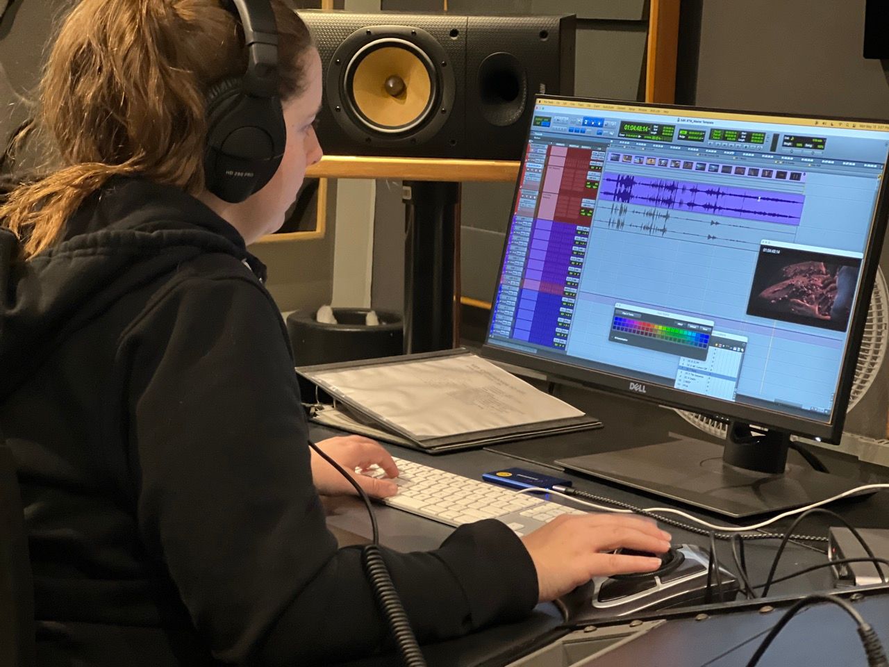 A woman wearing headphones is sitting in front of a computer monitor.