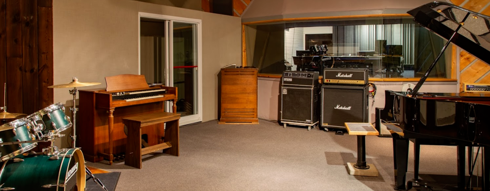 A recording studio with a piano , drum set , and organ.