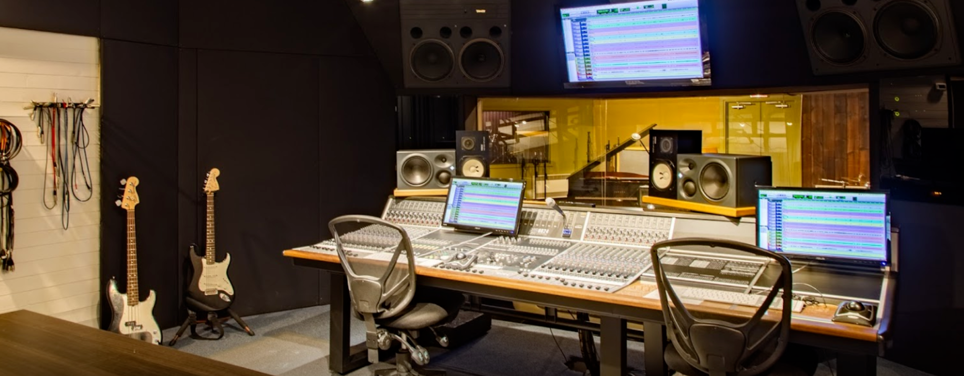 A recording studio with a lot of equipment and two guitars.