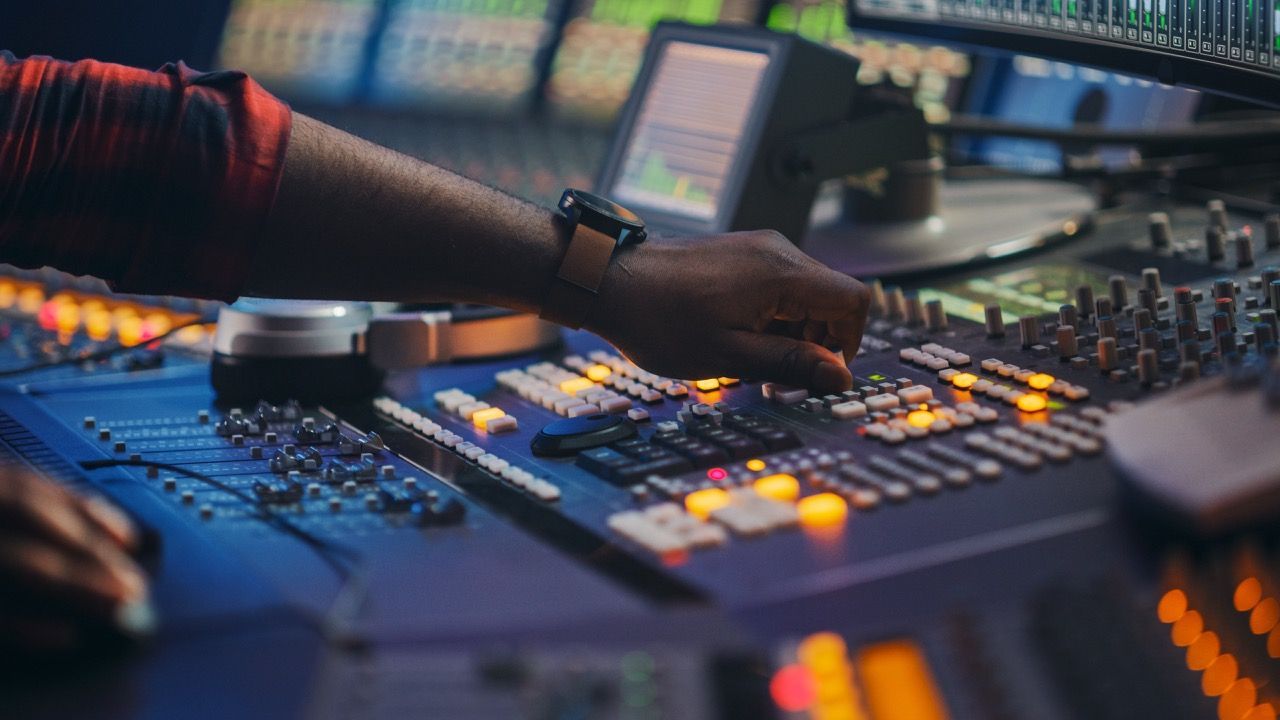 A person is working on a mixer in a control room.