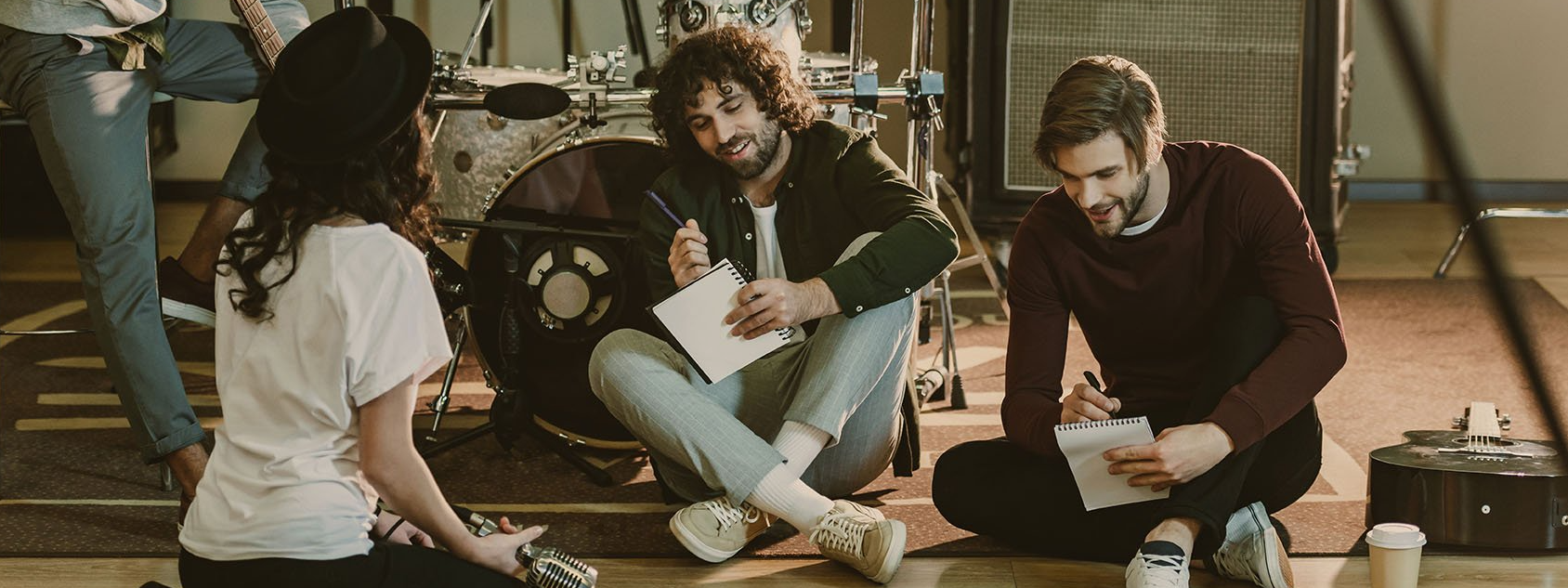 A group of people are sitting on the floor in front of a drum set.