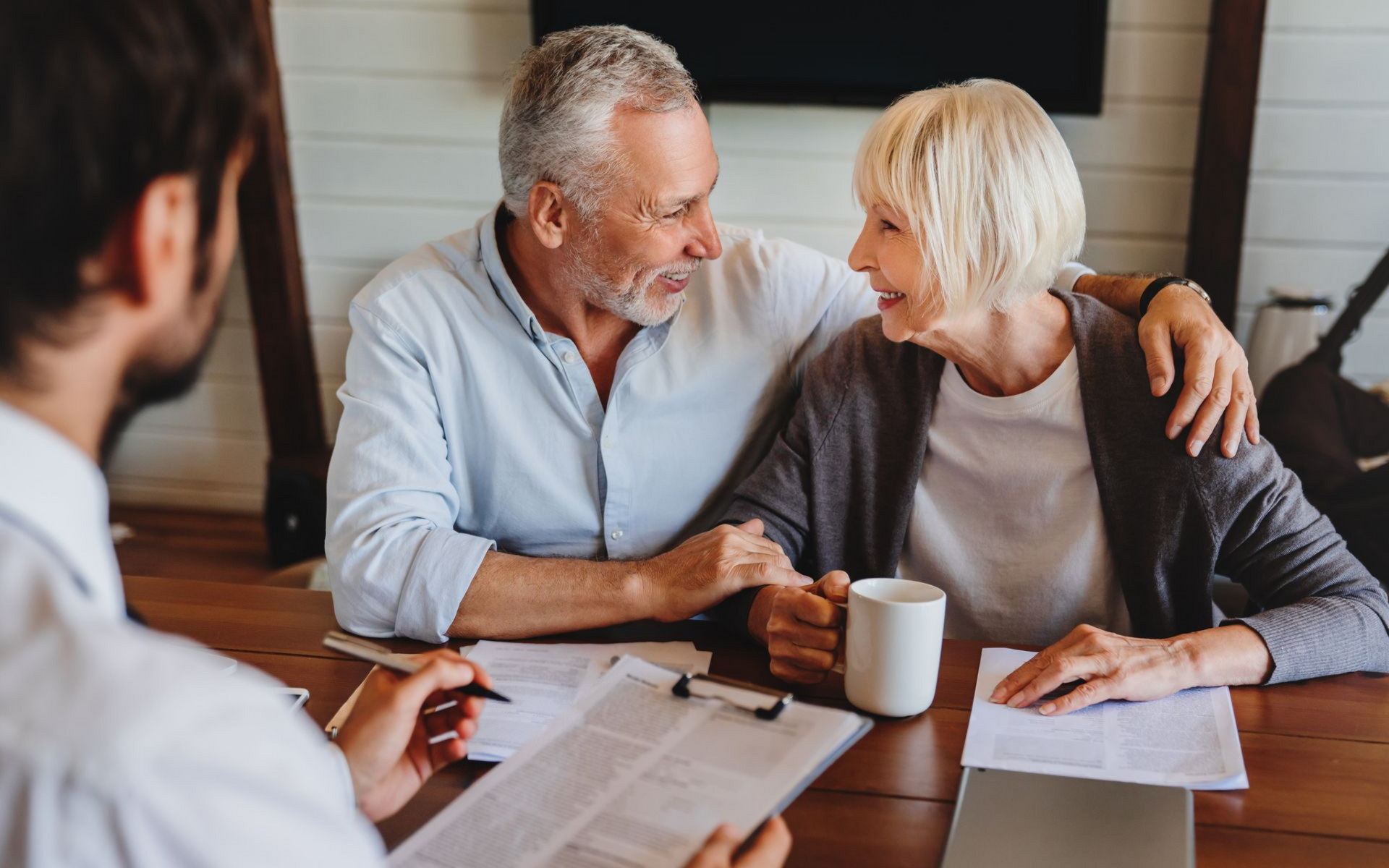 Senior couple smiling at each other while meeting with a lawyer to plan their estate