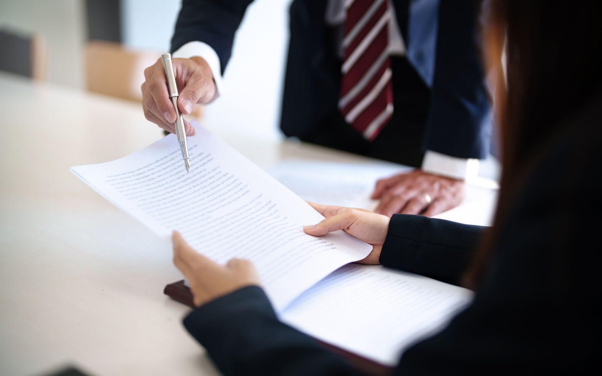 A person points a pen to a document held by another, possibly explaining a legal document.
