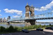 The John A. Roebling Suspension Bridge spans the Ohio River with the Cincinnati skyline in the background.