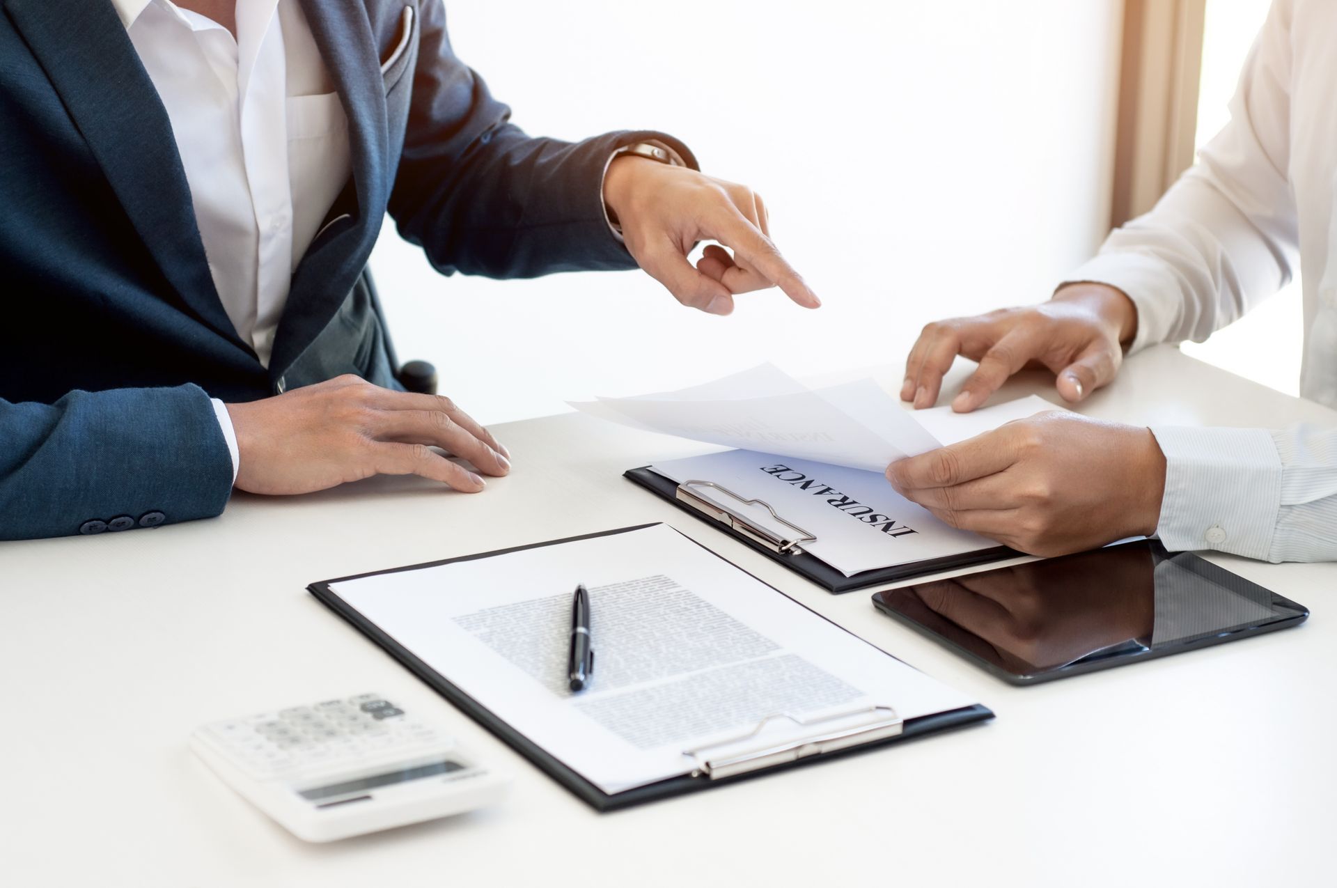 Two people reviewing documents at a table. One points while the other holds papers.