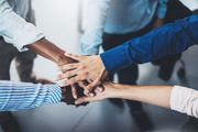 Hands stacked in a team huddle, symbolizing unity and collaboration.