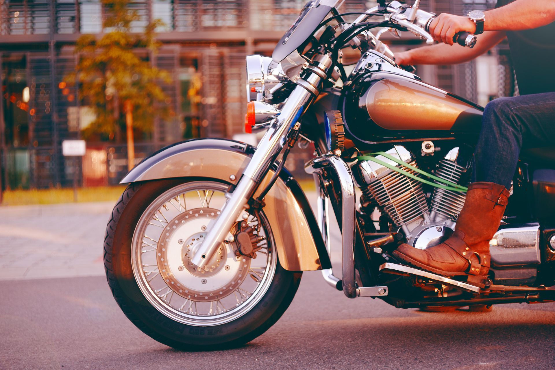 Person riding a brown and chrome motorcycle on a paved road.