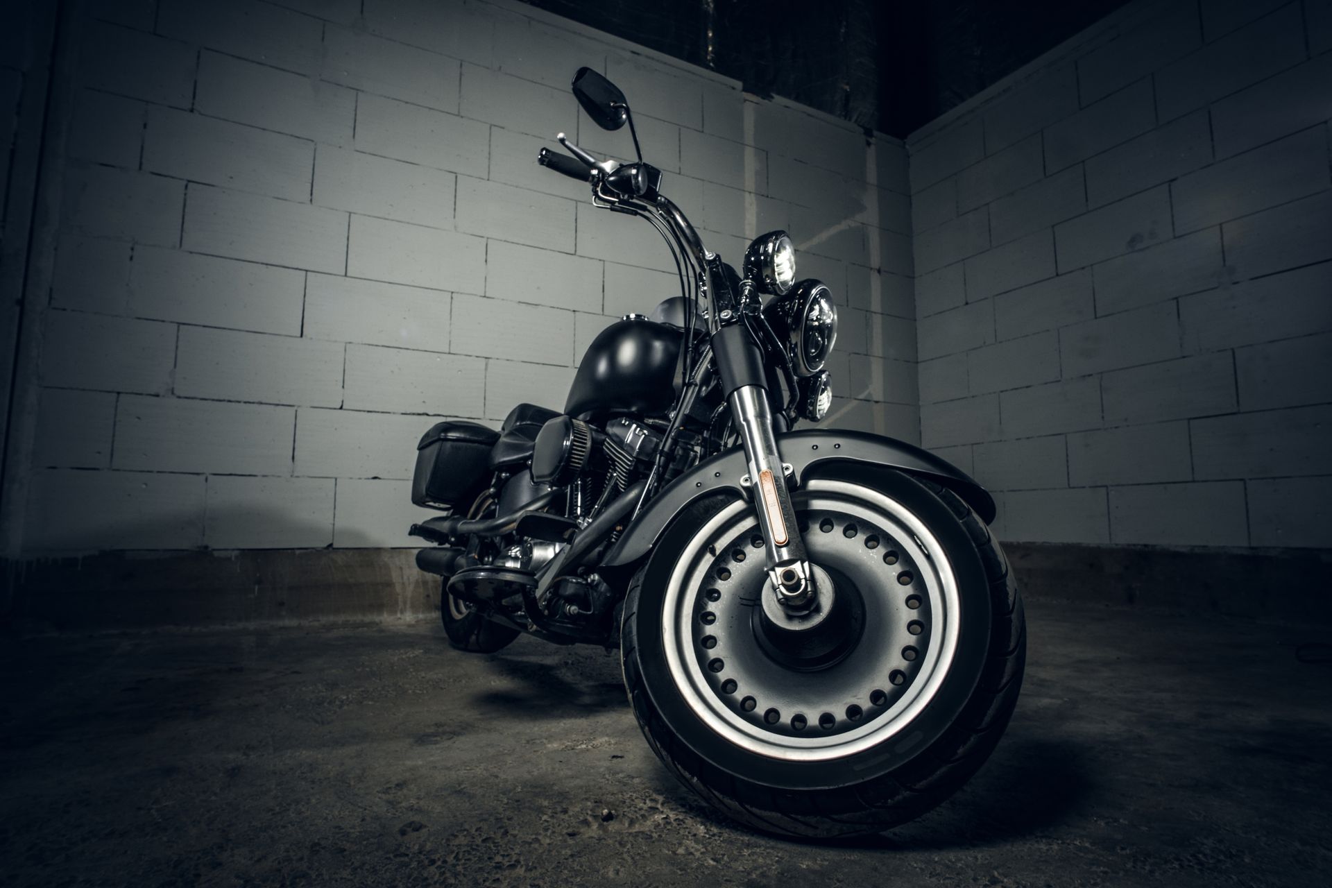 Black motorcycle parked in a dimly lit brick-walled garage.