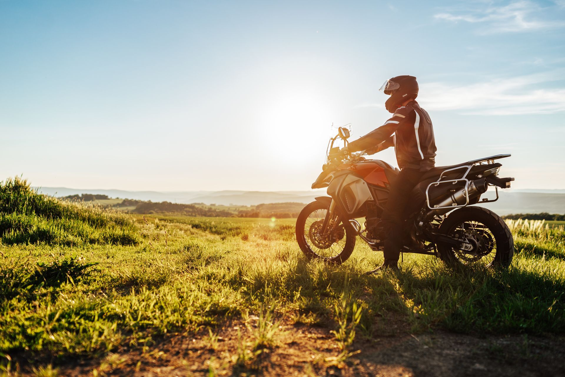 Person on a motorcycle overlooking a landscape at sunset.