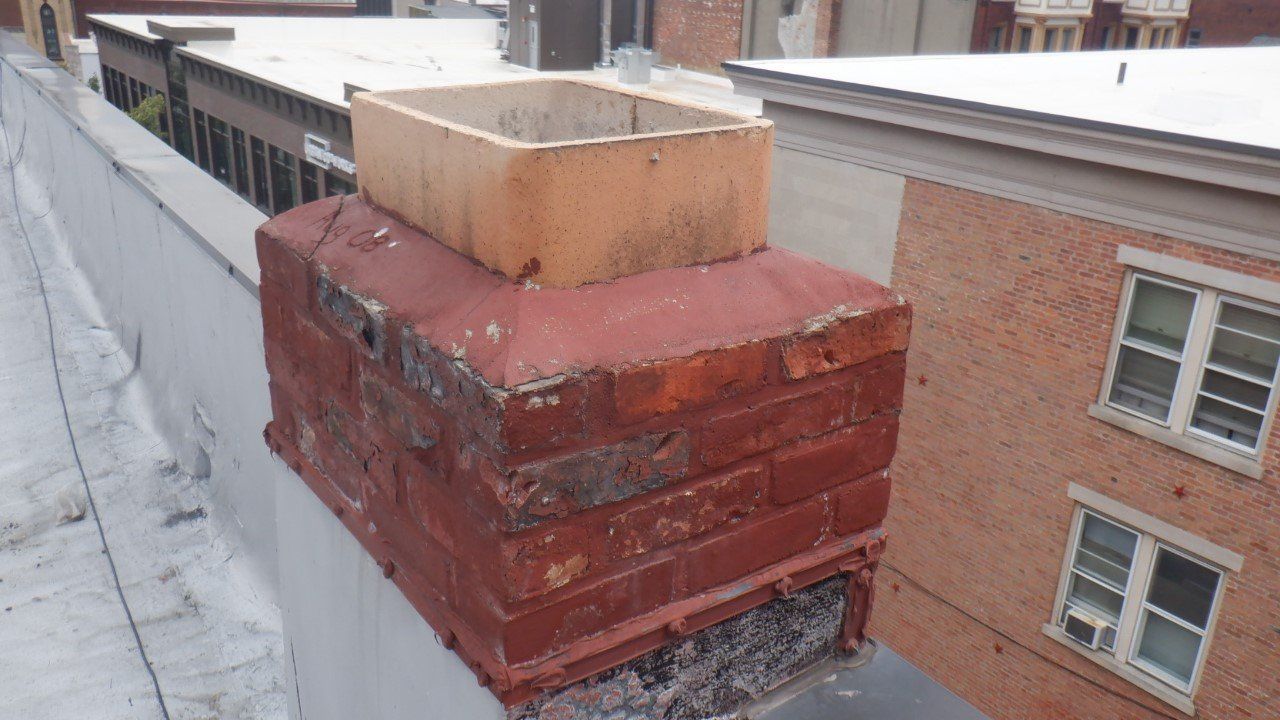 A brick chimney is sitting on top of a roof next to a building.