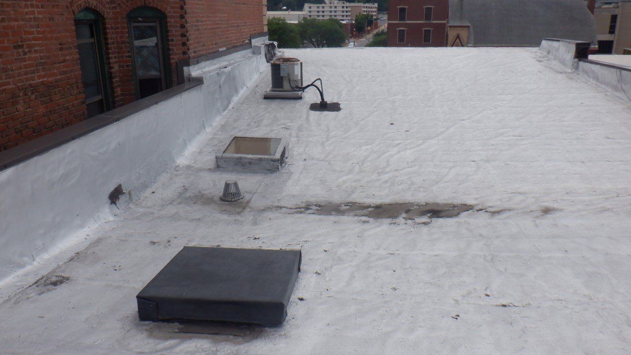 The roof of a building with a white roof and a black box on it.