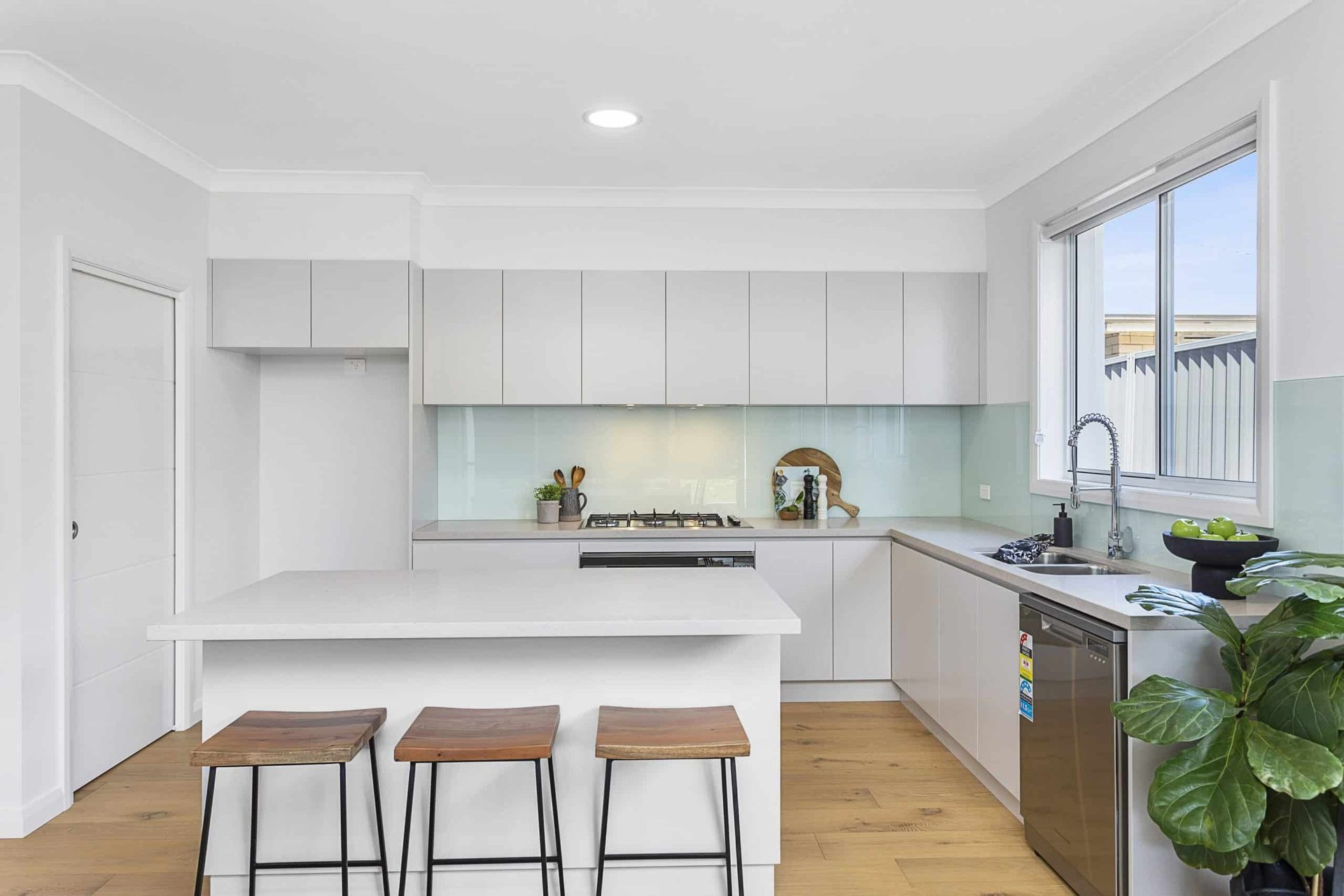 A Kitchen With White Cabinets, Stools, a Sink, and a Window — Evolution Building Group Dapto, NSW