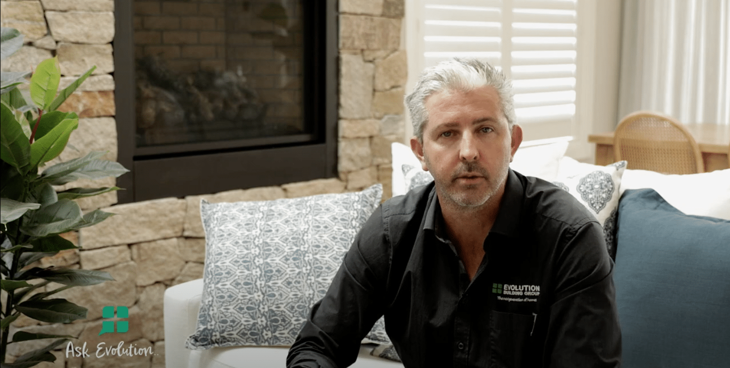A Man is Sitting on a Couch in a Living Room in Front of Fireplace — Evolution Building Group Dapto