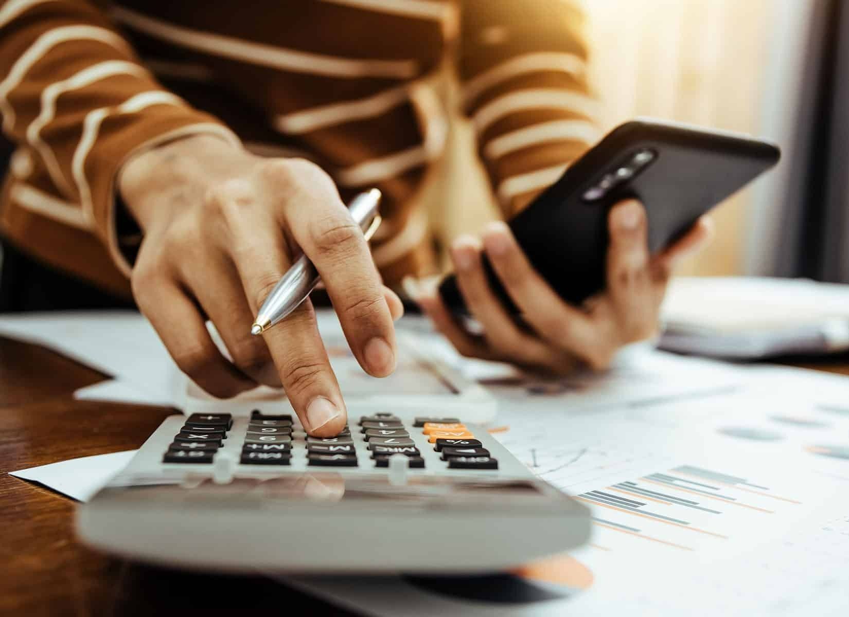 A Person is Using a Calculator While Holding a Cell Phone — Evolution Building Group Dapto, NSW