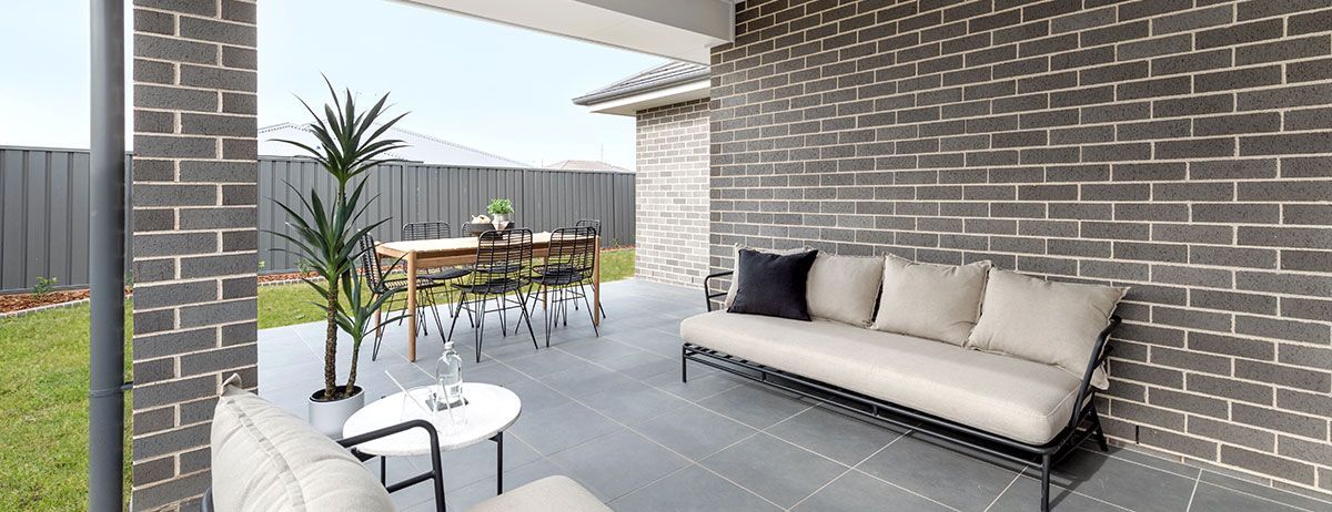 A Patio With a Couch, Table, Chairs and a Brick Wall — Evolution Building Group Dapto, NSW