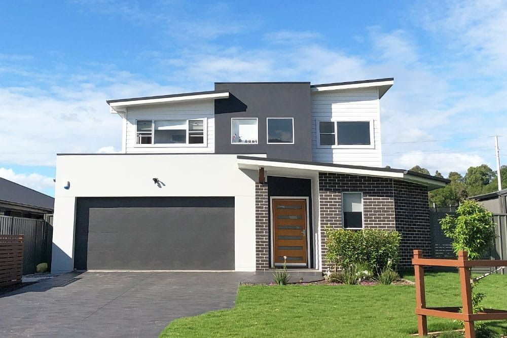 A Modern House with A Large Garage and A Wooden Fence in Front of It — Evolution Building Group Dapto, NSW