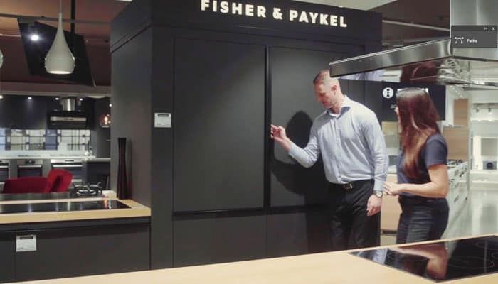 A Man and a Woman Are Standing in a Kitchen in Front of a Fisher & Paykel Sign — Evolution Building Group Dapto, NSW