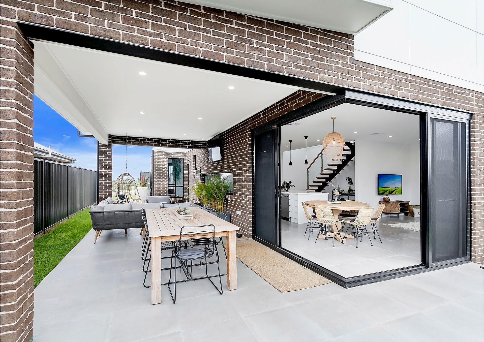 Patio with open sliding doors to a dining area; a wooden table with chairs, and brick and white building — Evolution Building Group In Mittagong, NSW