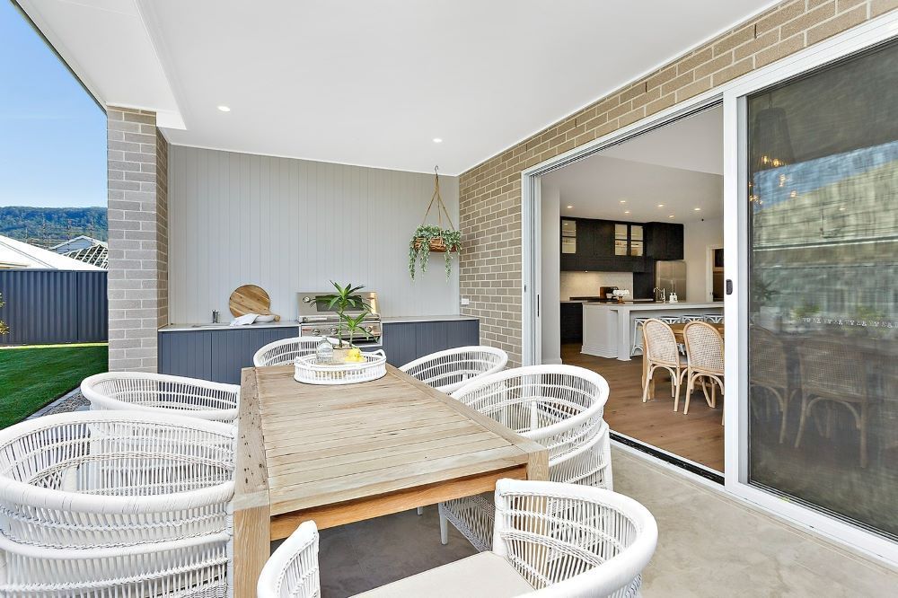 A Patio With a Table and Chairs and a Sliding Glass Door Leading to a Kitchen — Evolution Building Group Dapto, NSW