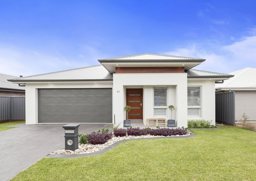 A White House With a Grey Garage Door and a Mailbox in Front of It — Evolution Building Group Dapto, NSW