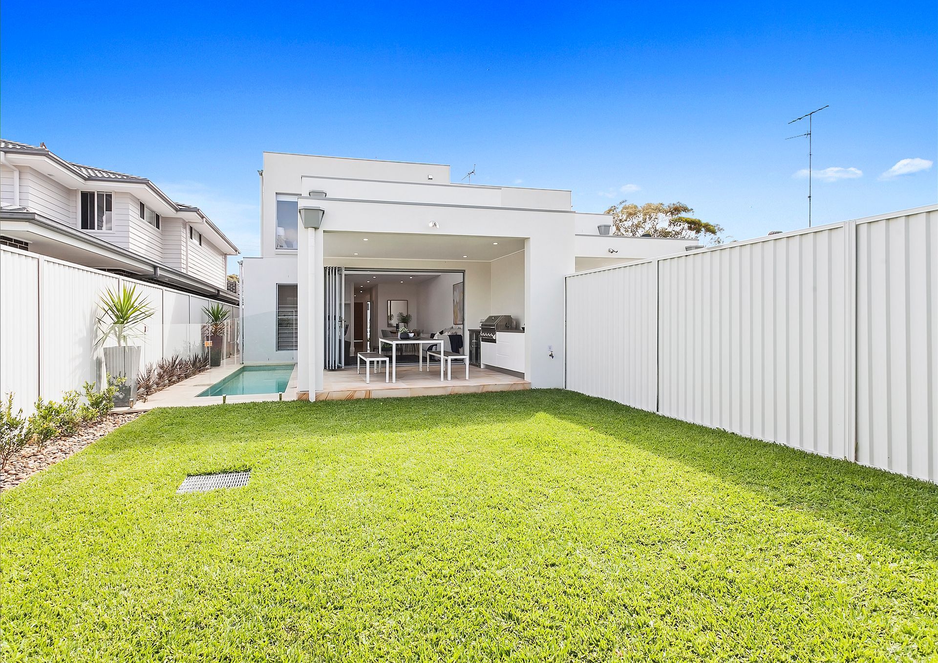 Backyard With Green Lawn, White Fence, and Covered Patio of a Modern House — Evolution Building Group in Dapto, NSW